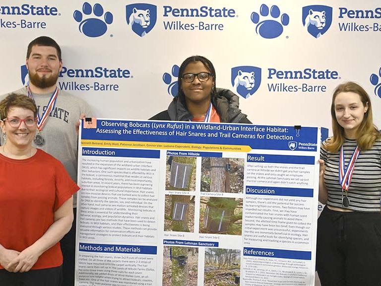 Student winners and a faculty member standing with a research poster.
