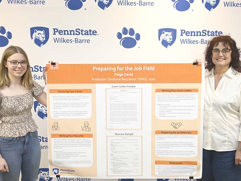 A winner and a faculty member standing with a research poster