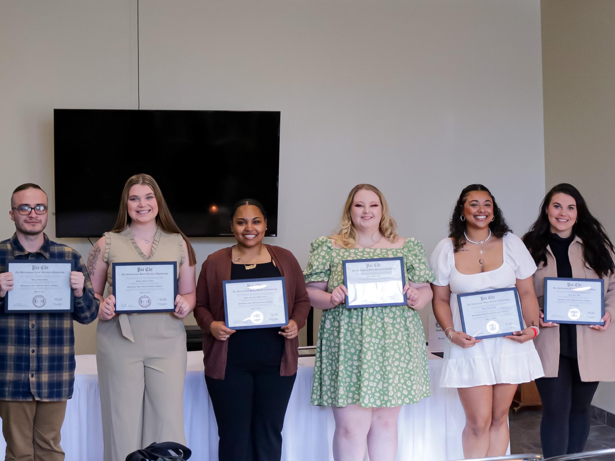 smiling students holding certificates