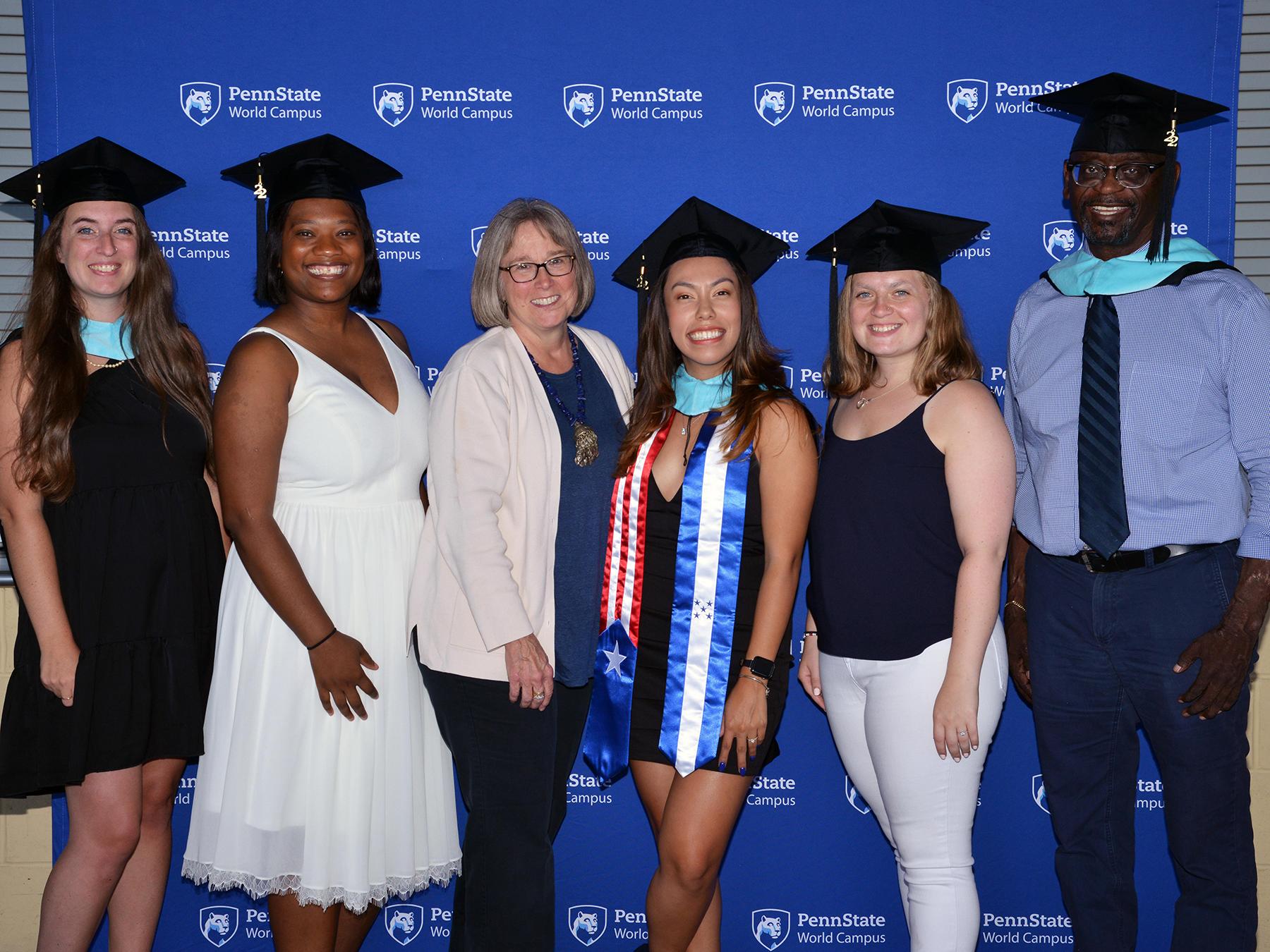 A group of six people pose in front of a blue background.