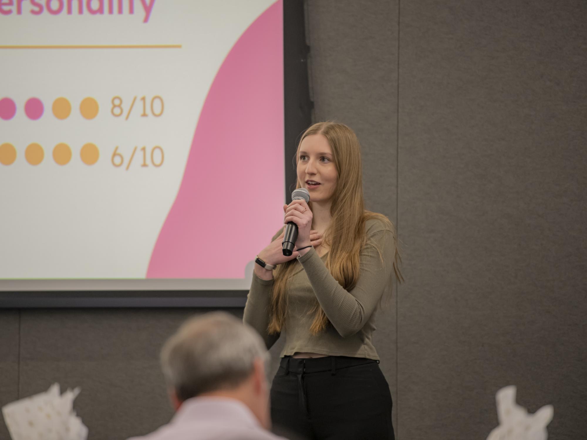 A female student speaks into a microphone during a presentation