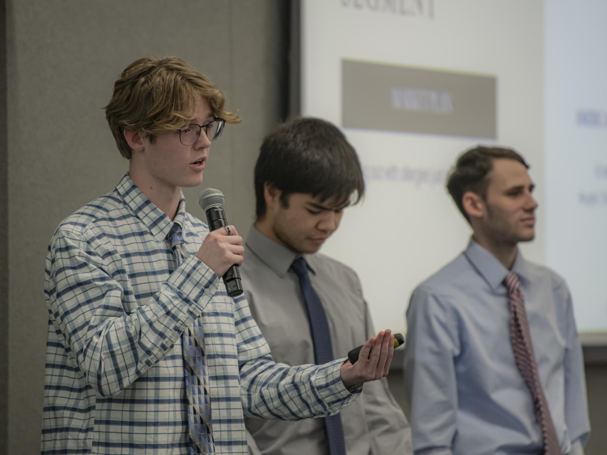 A male student speaks into a microphone during a presentation