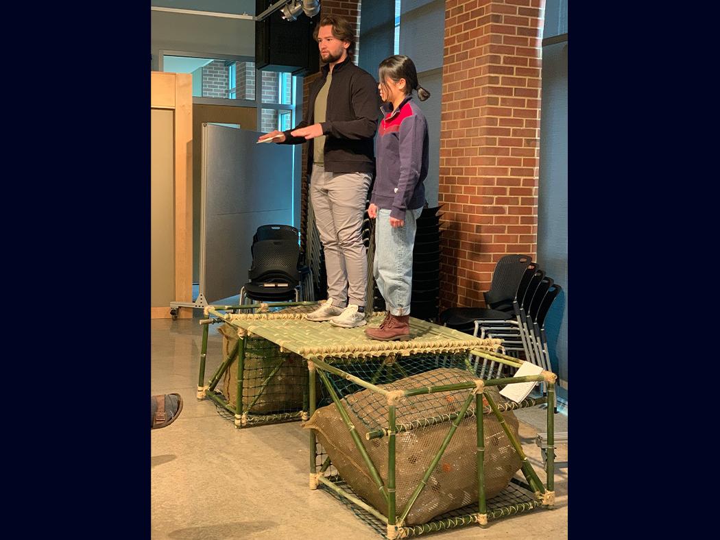 Two students stand atop a prototype they designed for the floating community of Clarevito.