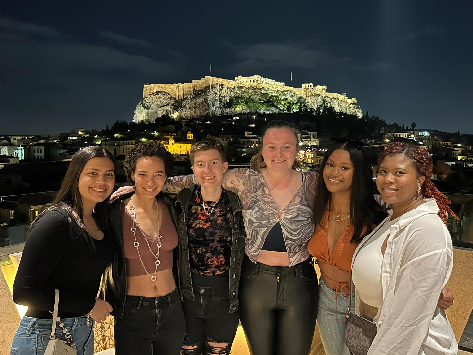 Group of Penn State students at a rooftop restaurant with the Acropolis behind them, in Athens, Greece.