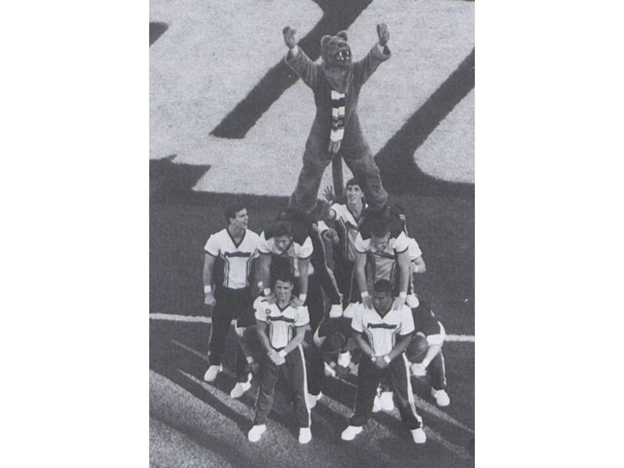 A group of male cheerleaders holds the Nittany Lion on the sideline of a football game in 1998