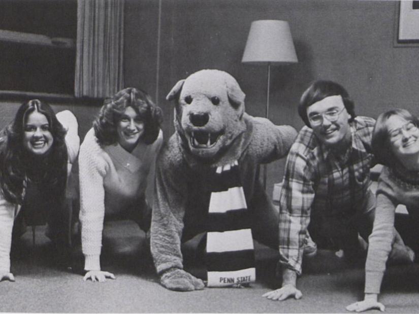 The Nittany Lion poses doing one-armed pushups with four students.