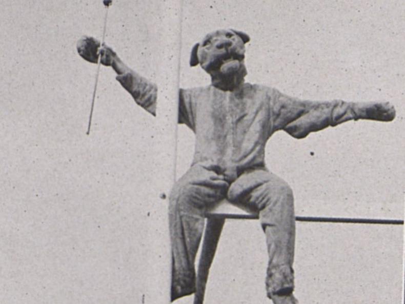 The Nittany Lion sits on top of a goal post, holding a baton, in 1940.