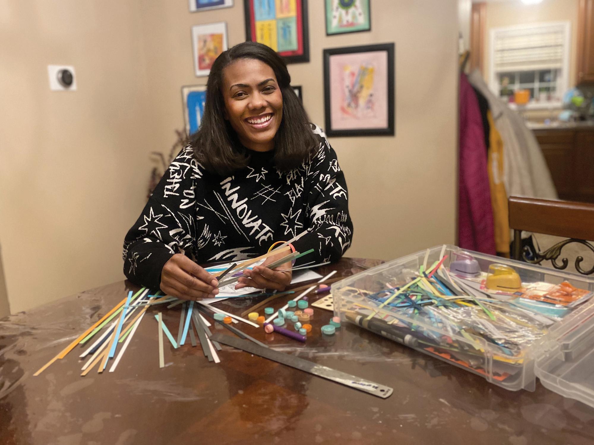Ashley Patterson sits at a table while paper quilling.