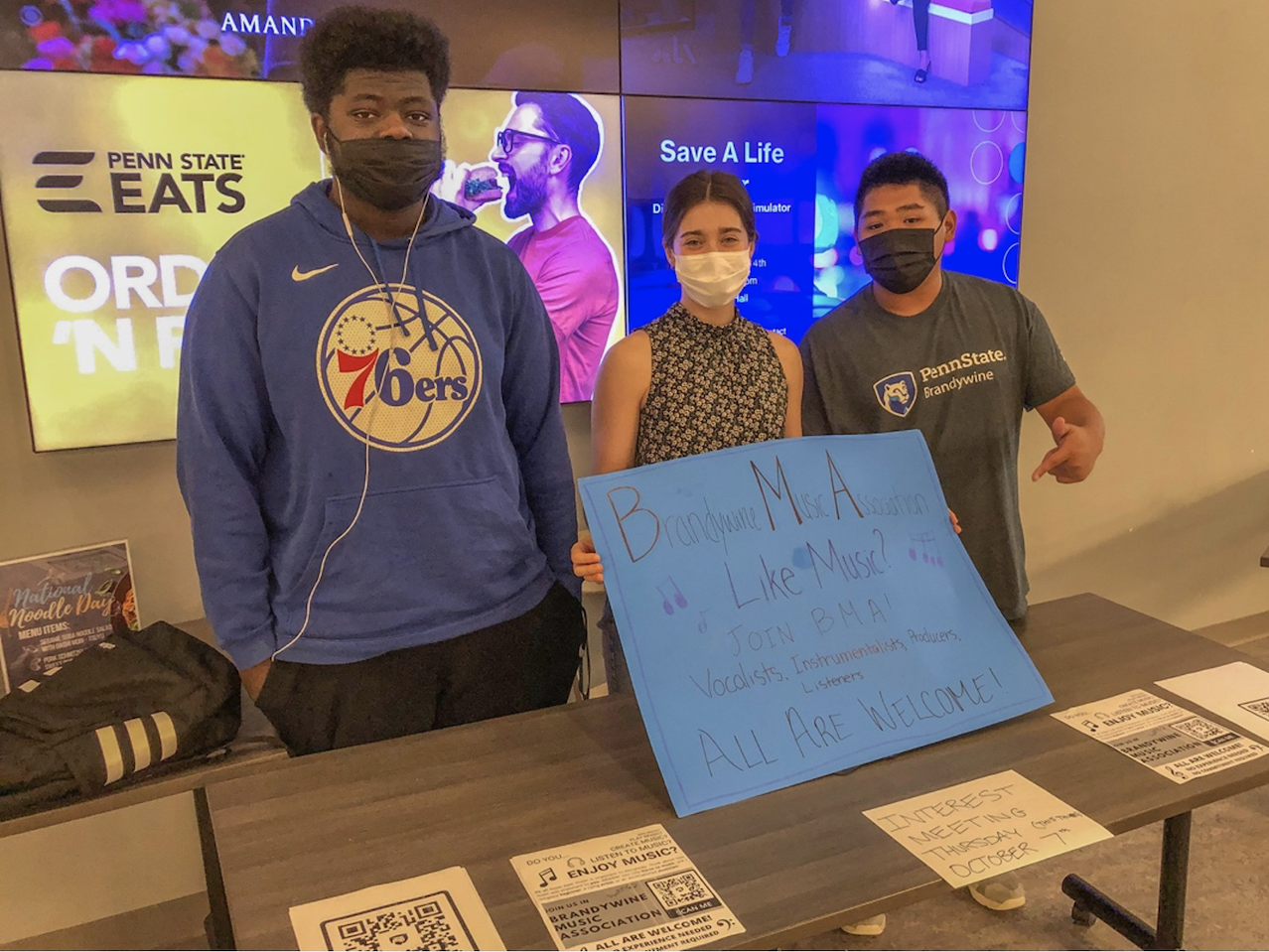 Three people wearing masks holding a sign to join BMA
