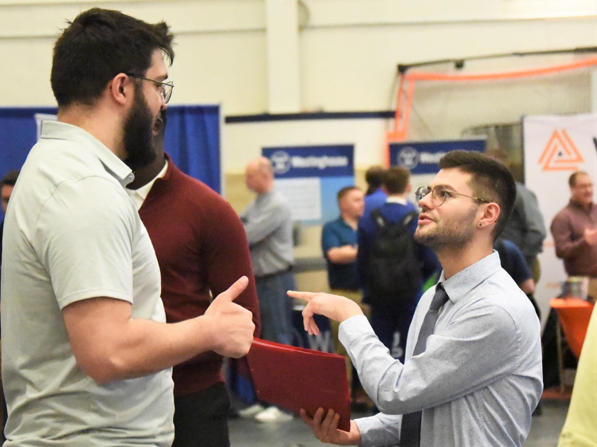 A student gestures while talking with a recruiter at Penn State Behrend's spring Career and Internship Fair.
