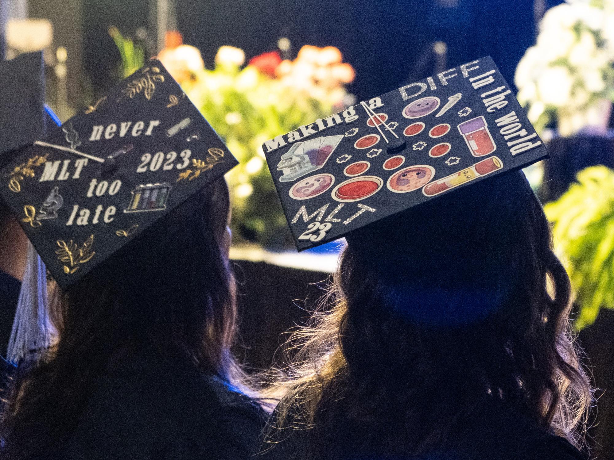 Two graduation caps decorated with stickers and text.