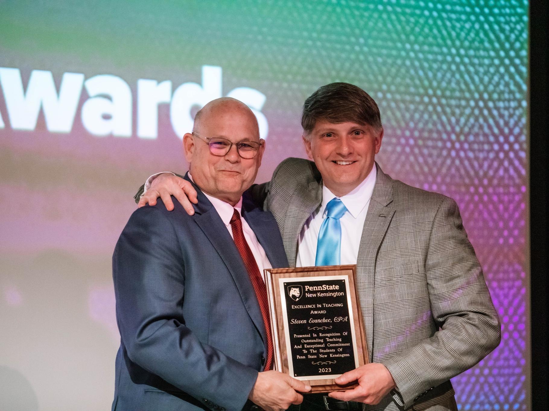 Two people standing while holding a plaque