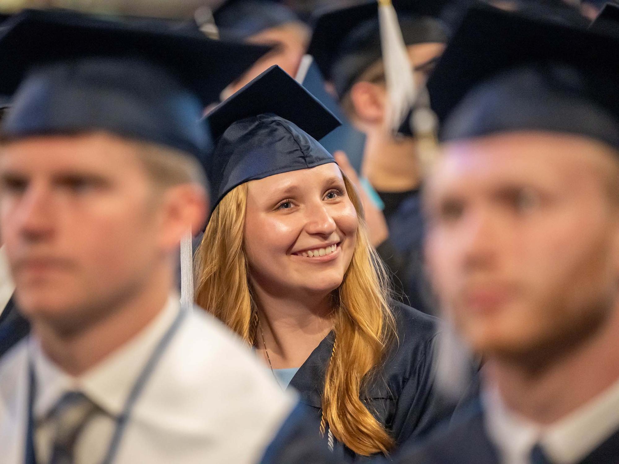 A female graduate smiles in her seat at Penn State Behrend's spring commencement ceremony.