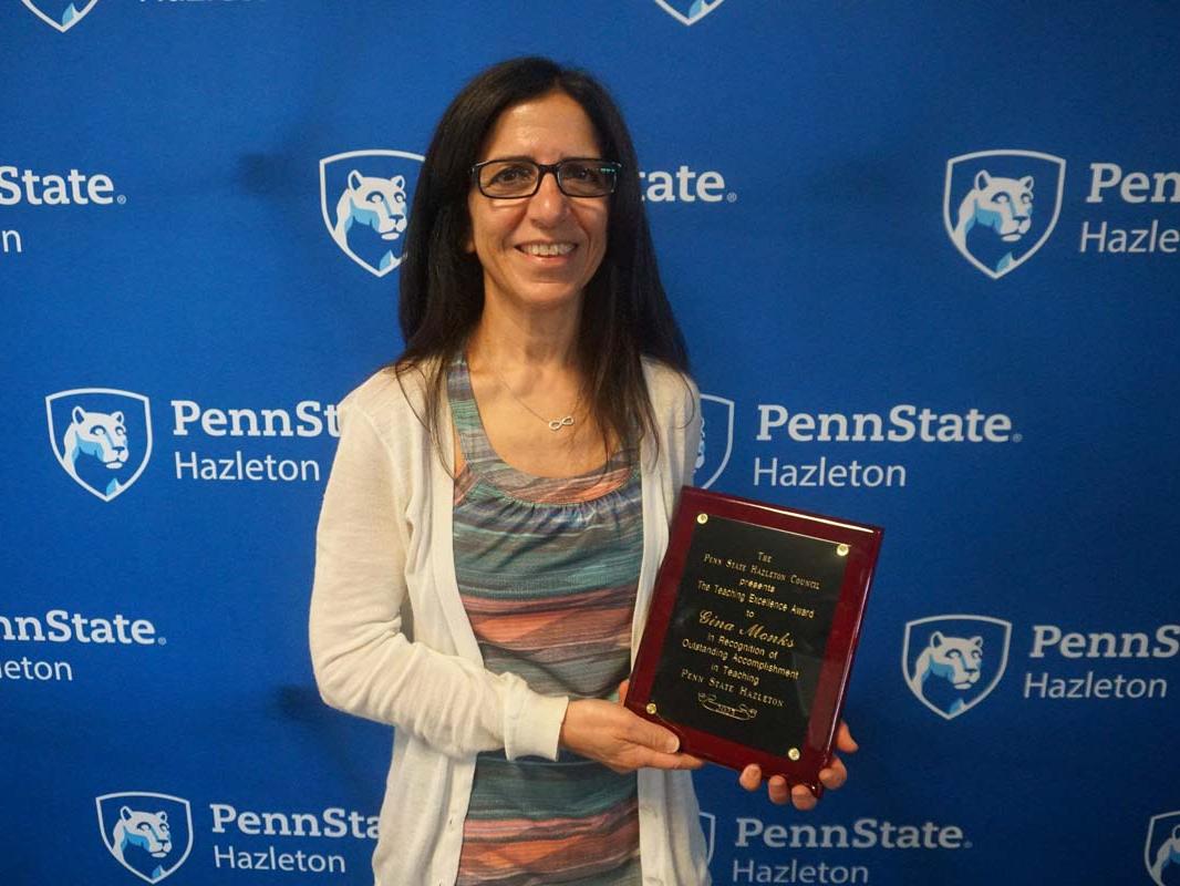 Woman smiling and holding plaque.