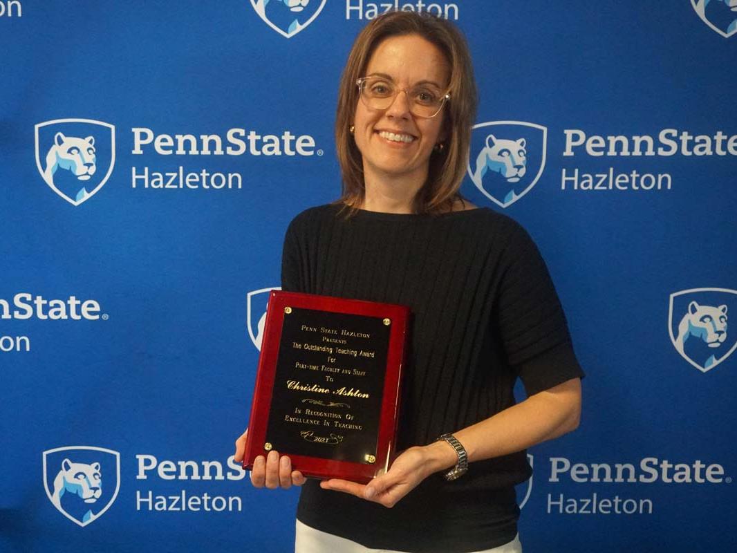 Woman smiling and holding plaque.