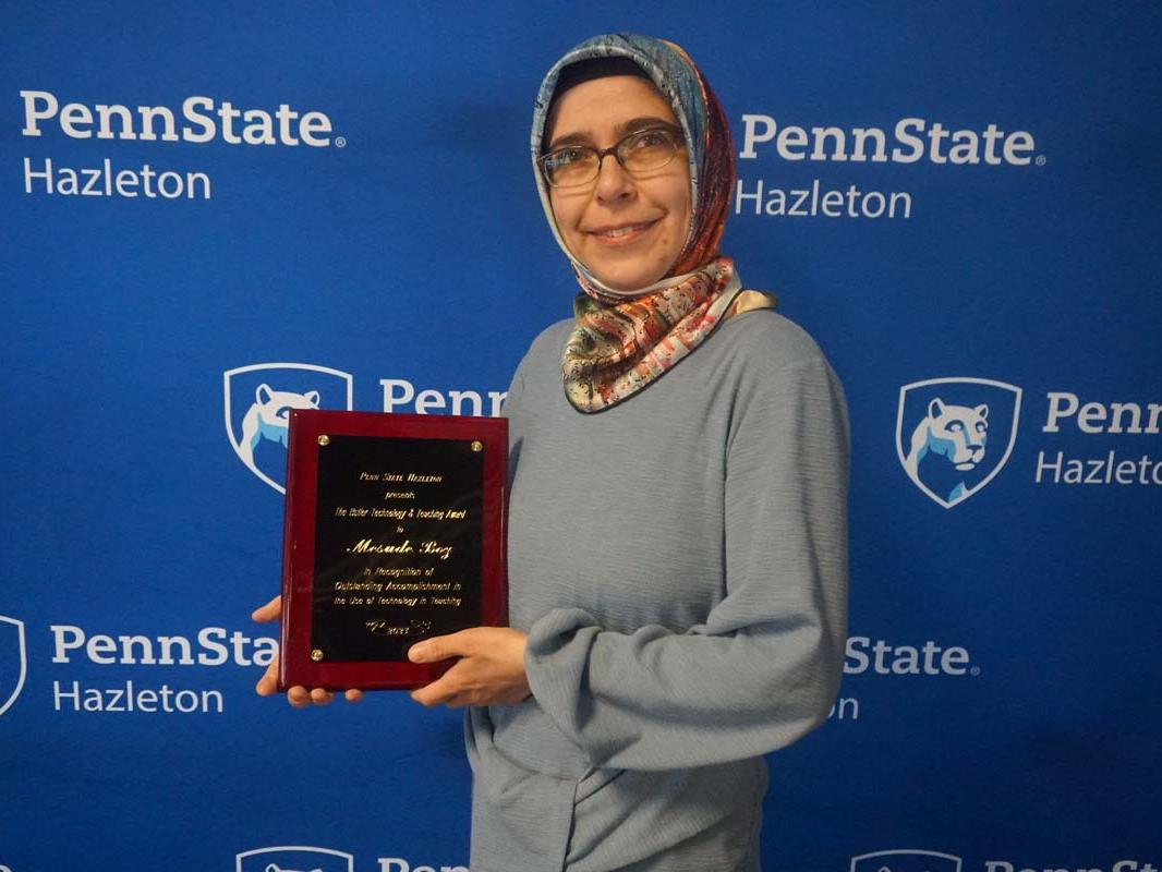 Woman smiling and holding a plaque.