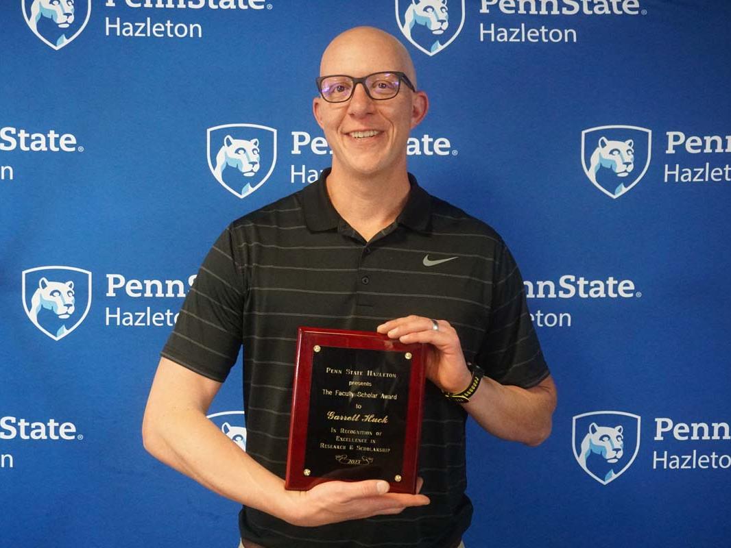 Man smiling and holding plaque.