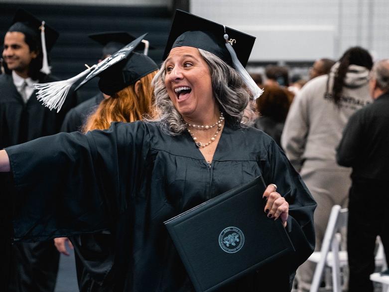 Graduate points and smiles holding diploma