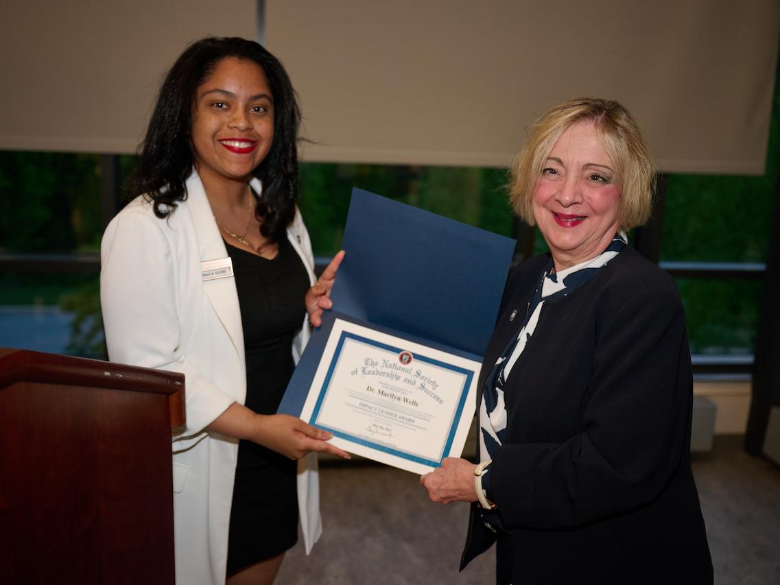 woman holding certificate and standing next to woman