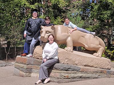 Two adults and two children pose in front of the Nittany Lion Shrine.
