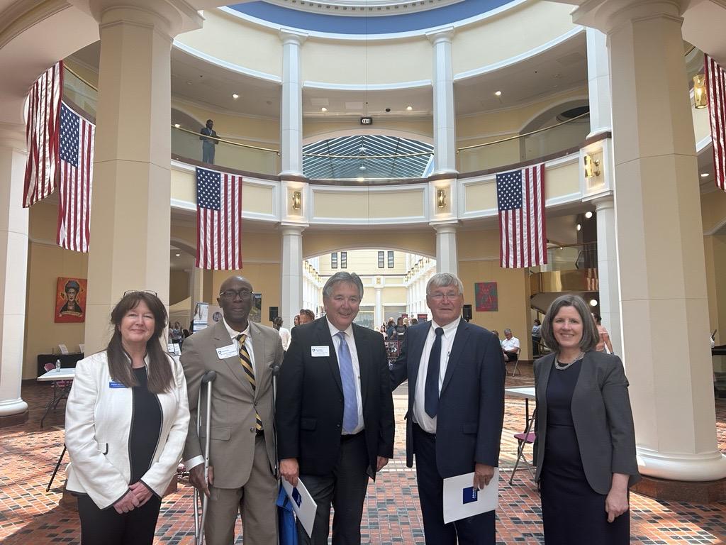 group of people standing in front of American flags in Pennsylvania state capitol building