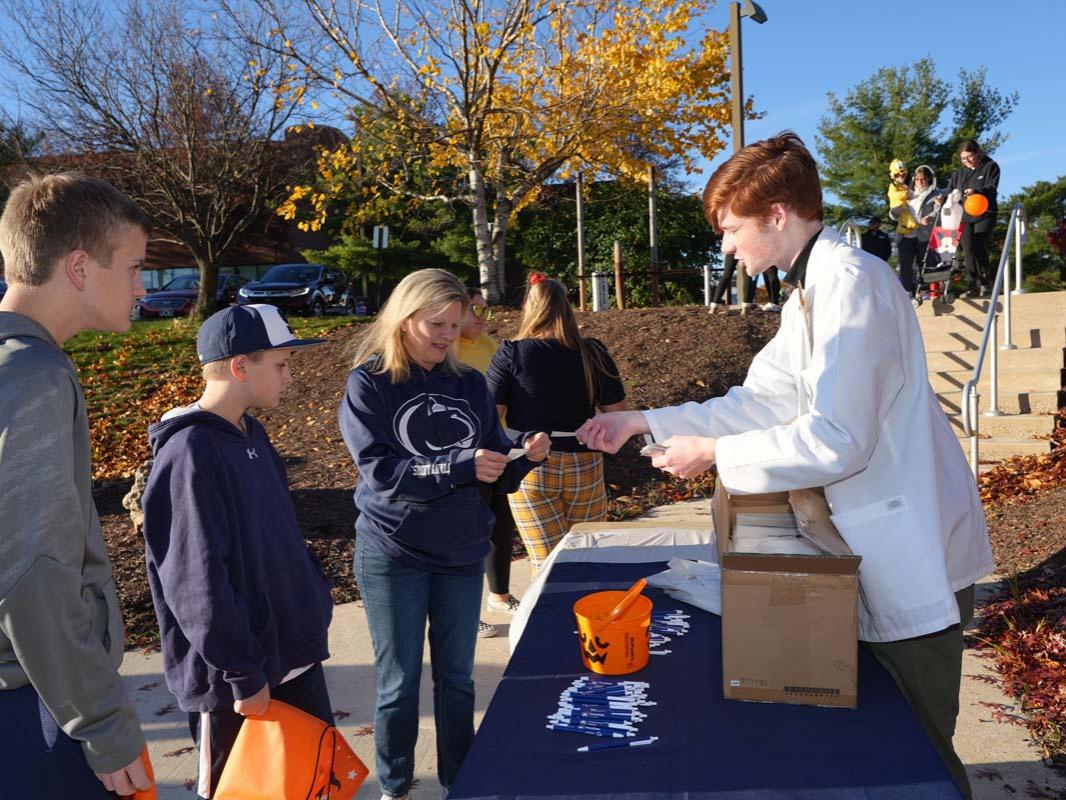 Family receiving a ticket at a table from a male student in a white coat.