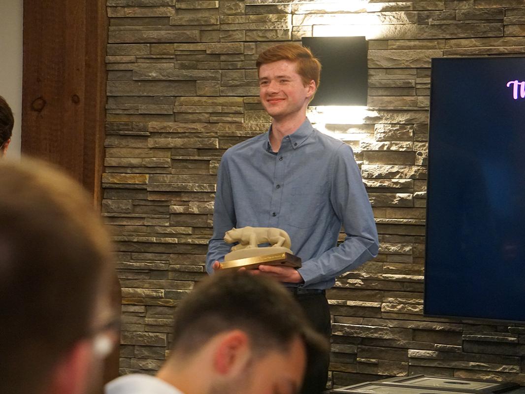 Student in blue dress shirt holding small statue of Nittany Lion.