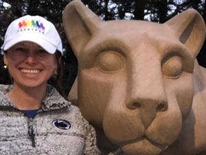 A woman poses next to the Nittany Lion Shrine.