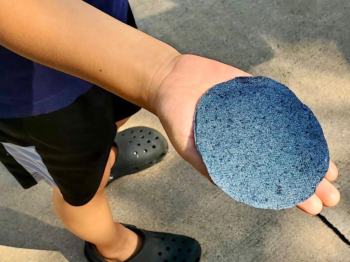 child's hand holding round handmade paper disk