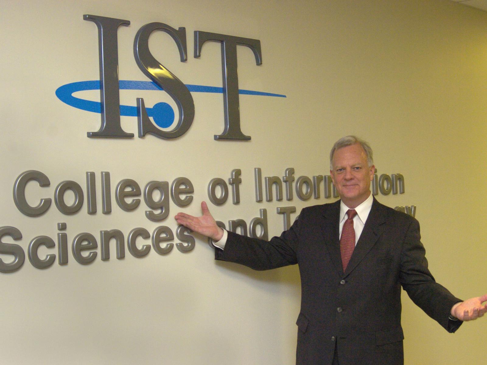 A photo of Jim Thomas in front of the IST name on a wall