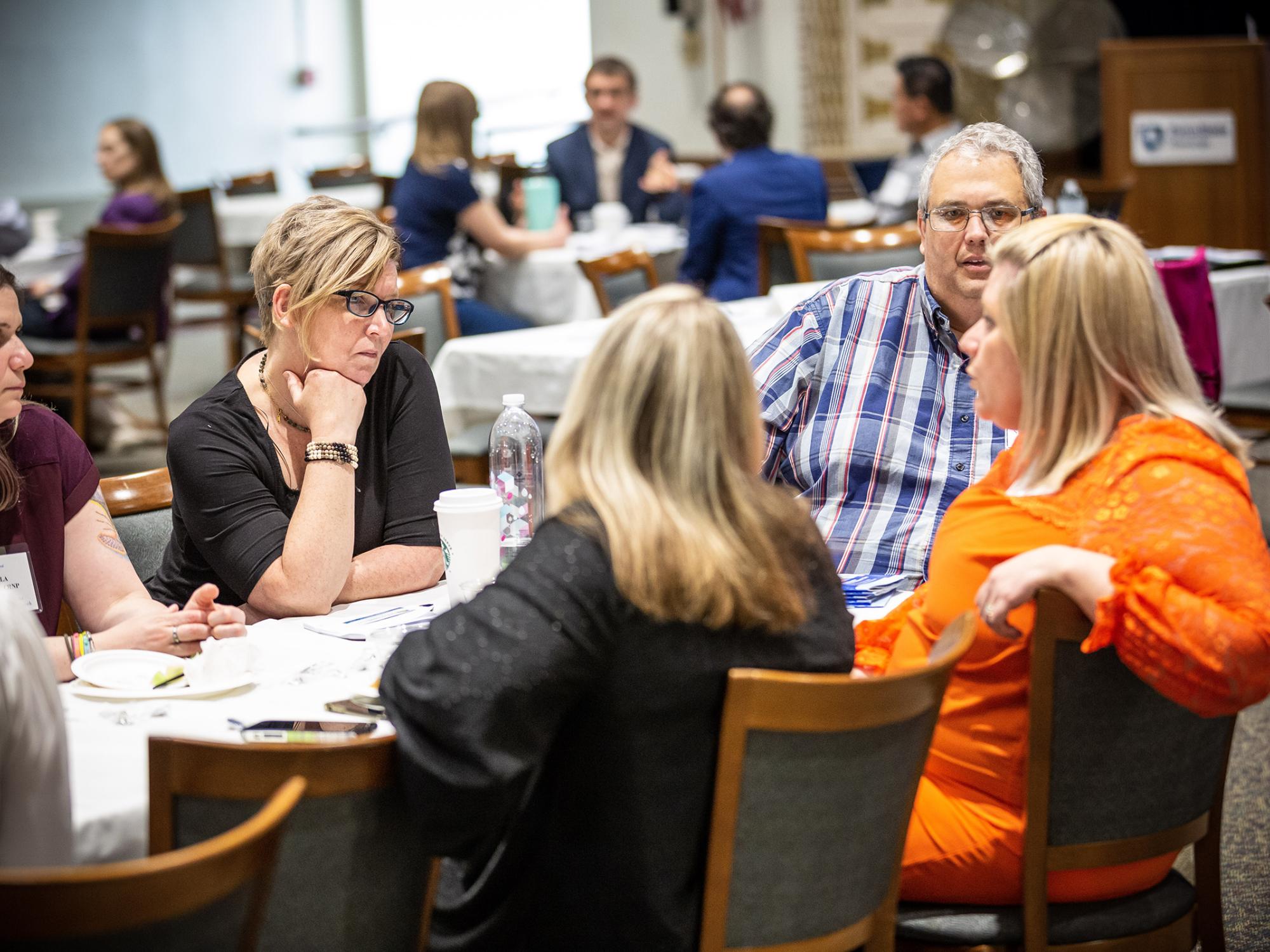 A group of people collaborate around a table at a conference.