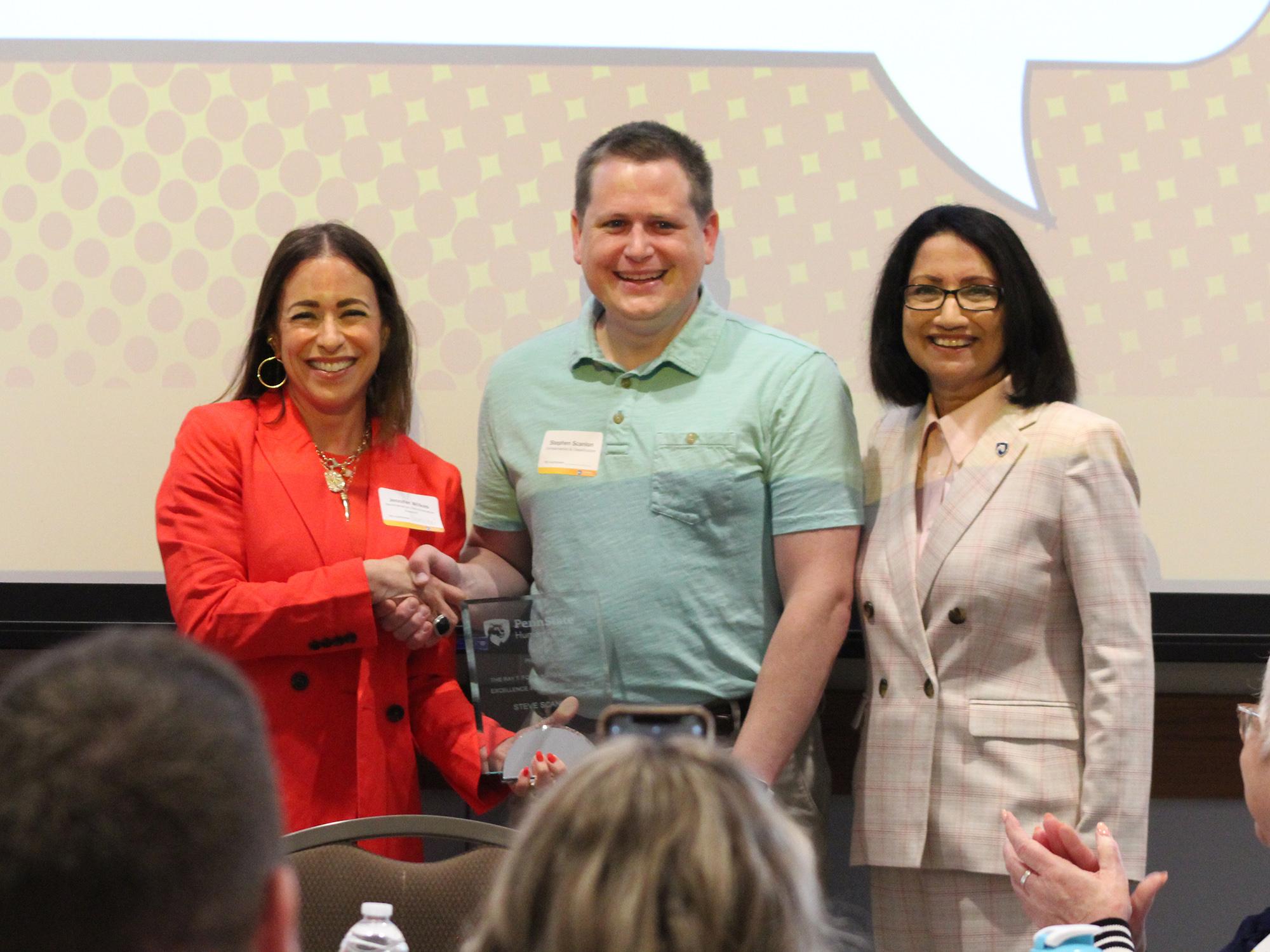 Jennifer Wilkes, Steve Scanlon and President Neeli Bendapudi smiling and holding the Fortunato award.