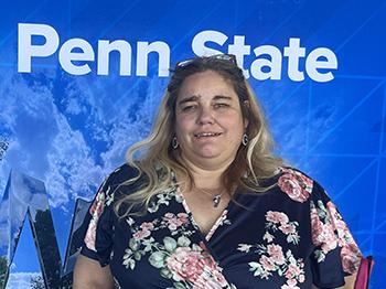 A woman stands in front of a Penn State-themed background.