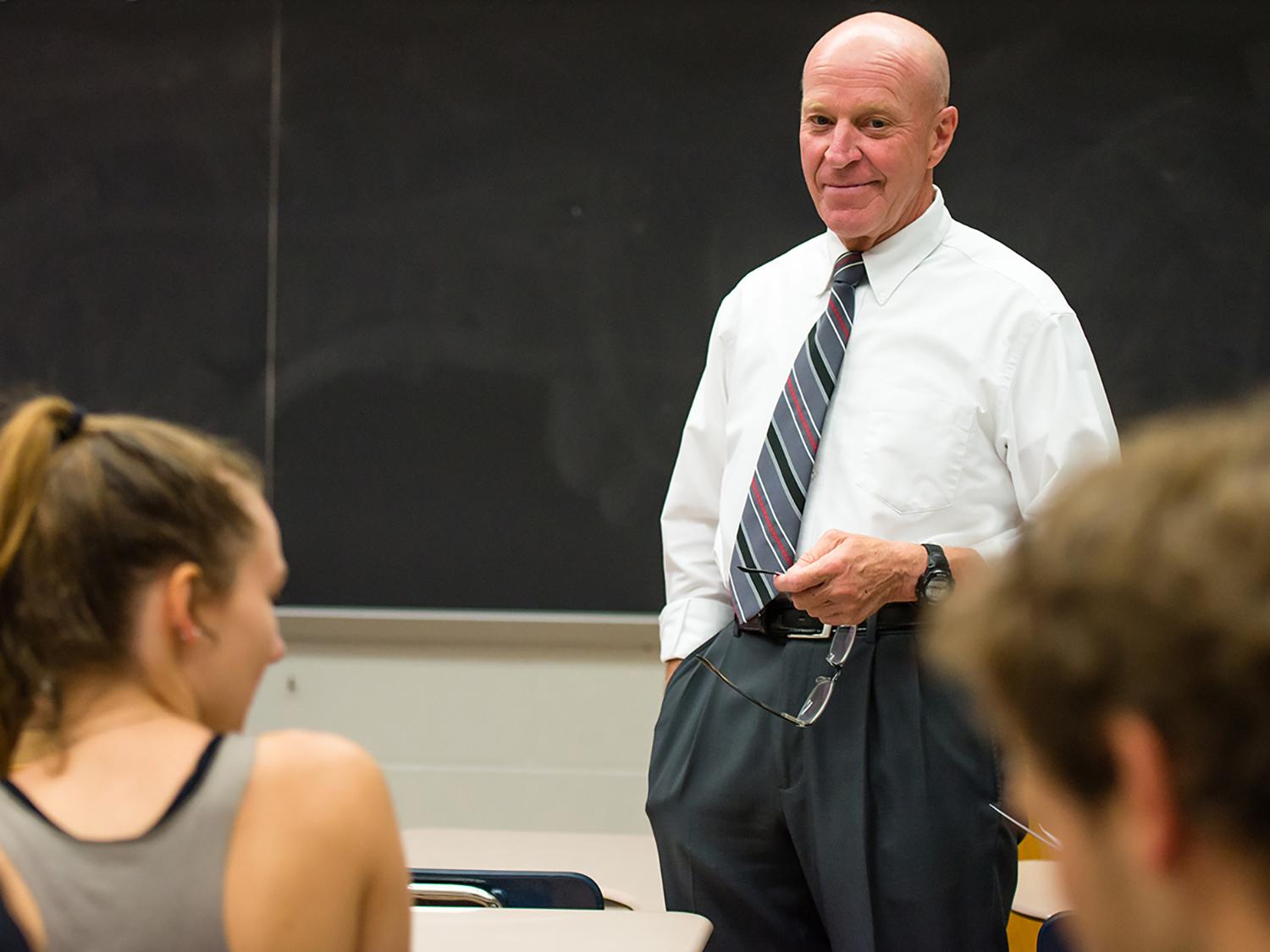 Bob Novack stands in a classroom of students