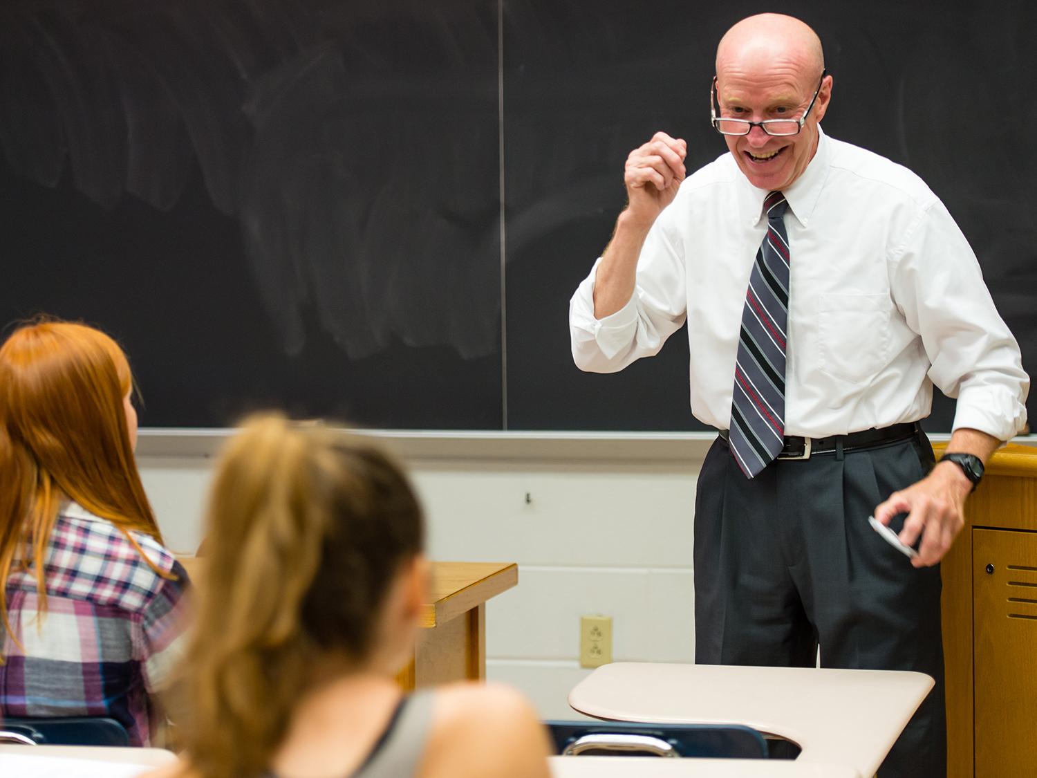 A photo of Bob Novack standing in class and smiling
