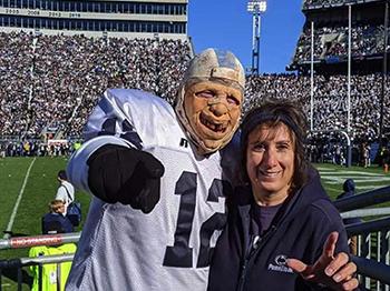 A woman stands next to a football fan at Beaver Stadium.