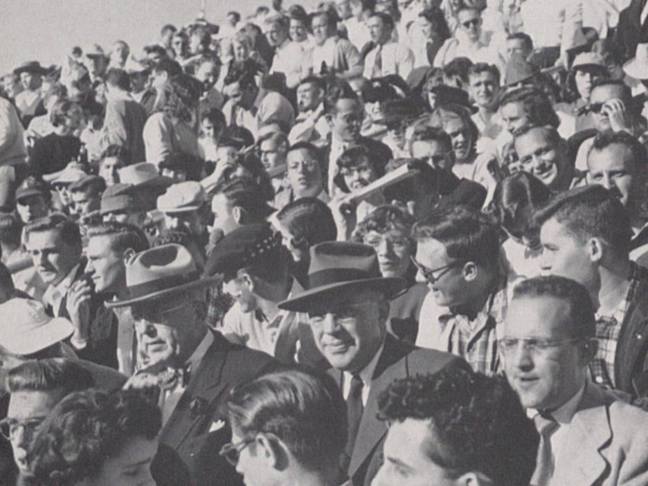 A black and white photo of football fans in the stands in 1954.