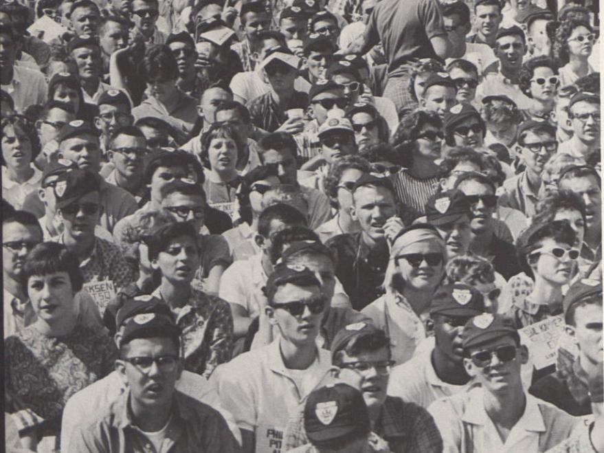 A black and white photo of football fans in the stands in 1961