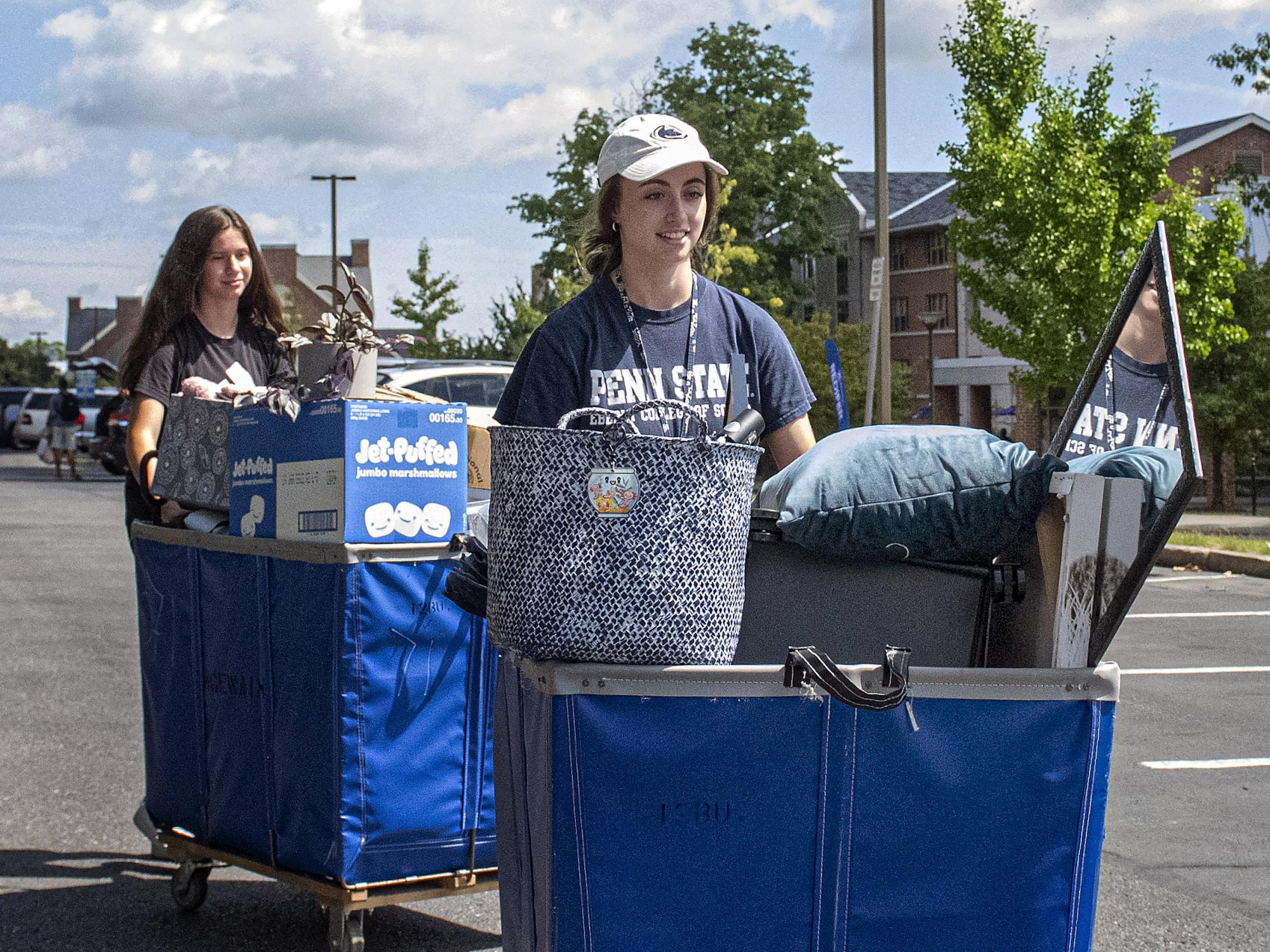 Two female students wheel bins containing their belongings on move-in day in 2022