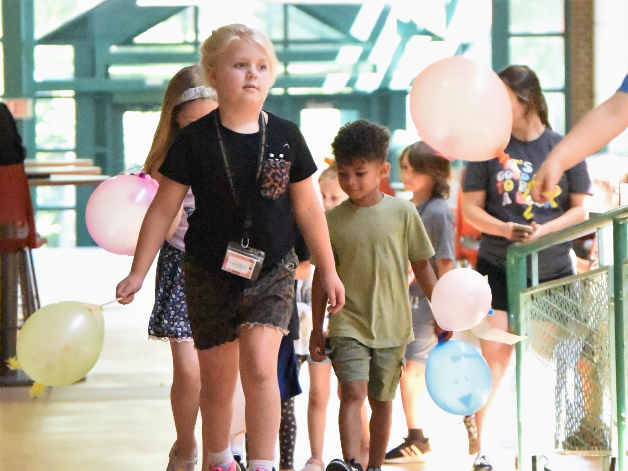 A group of children carry balloons in a parade at Penn State Behrend.