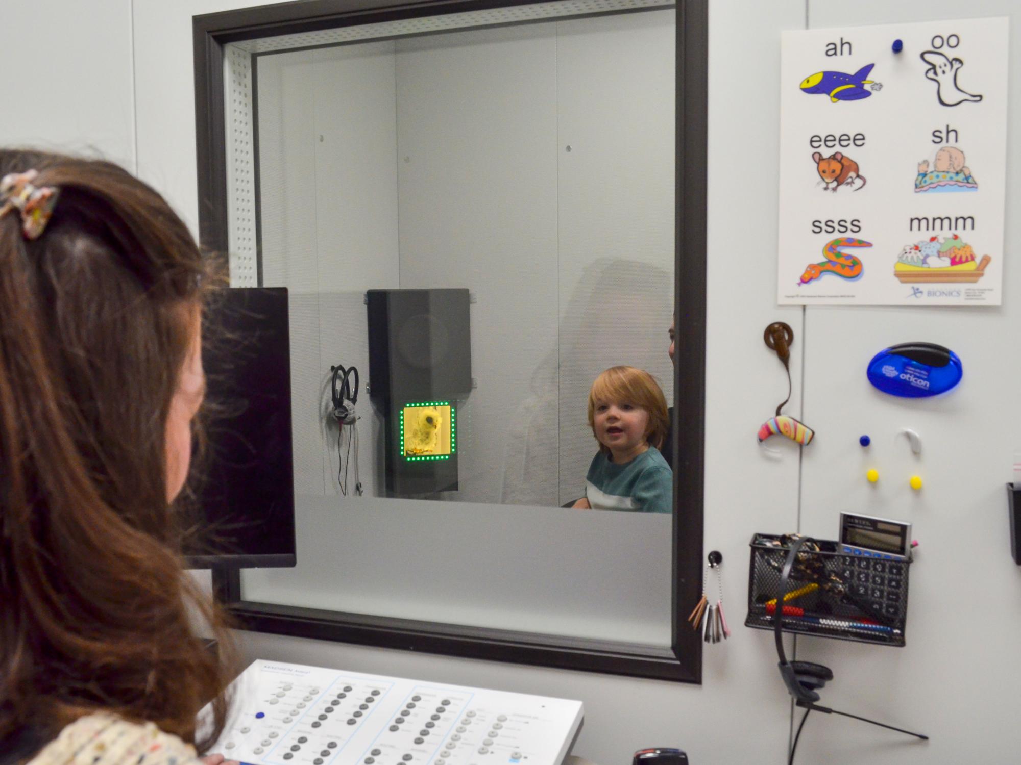 A child looks out of a sound proof room