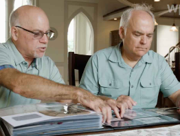 Two people sitting at a table looking through photos.