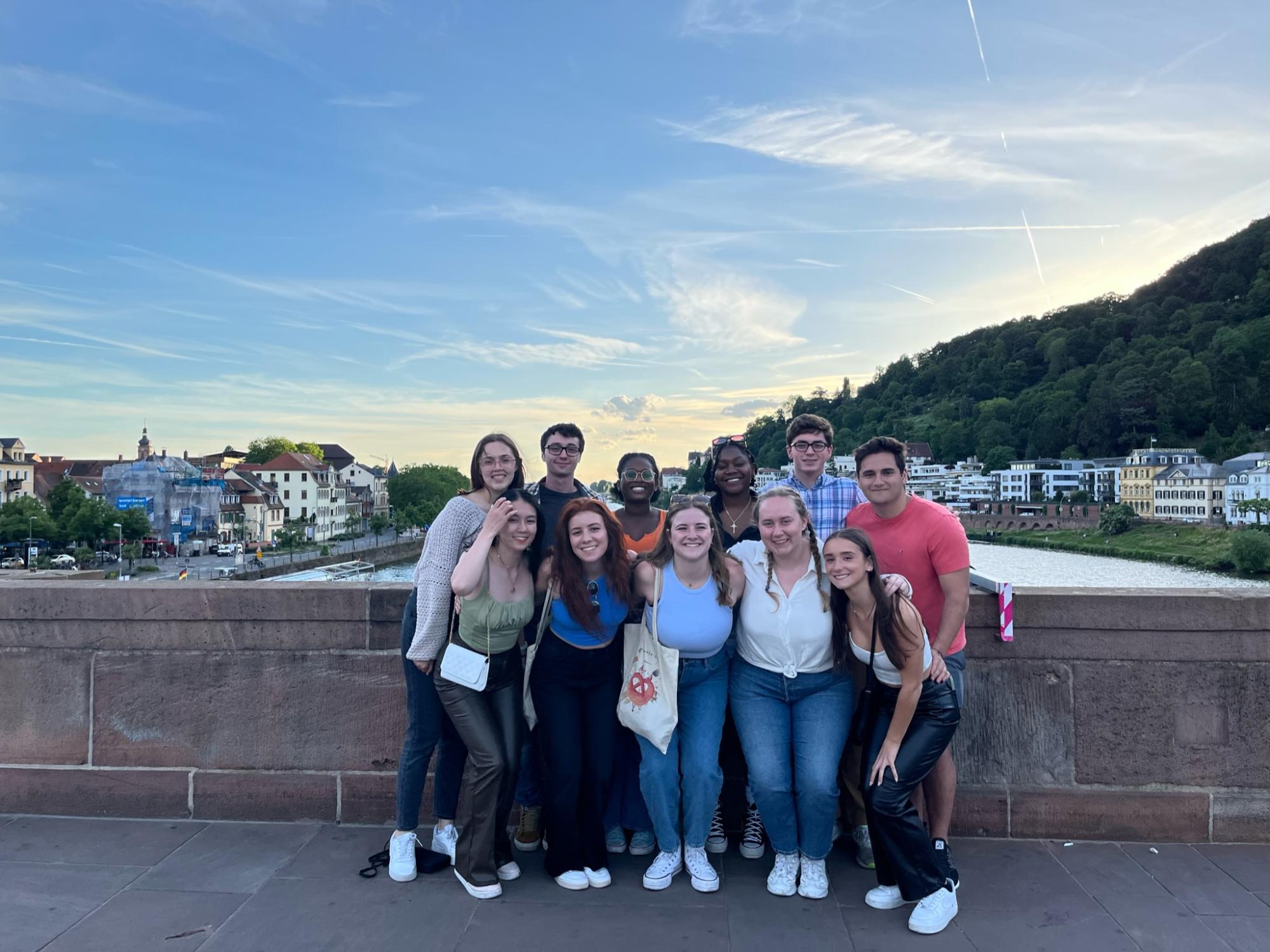 A group of 8 students posing for the camera on a bridge