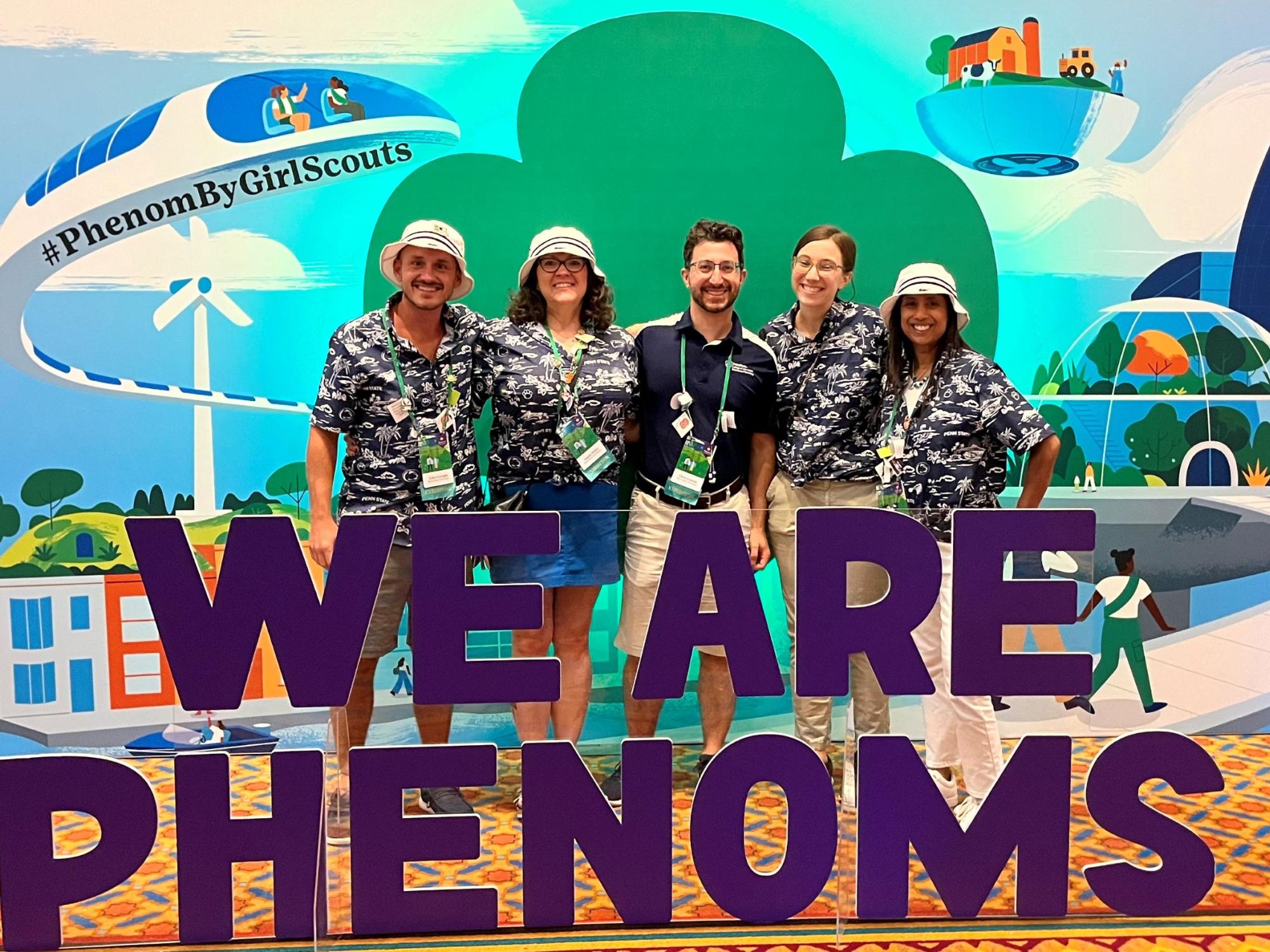 five people in matching outfits pose with convention signage