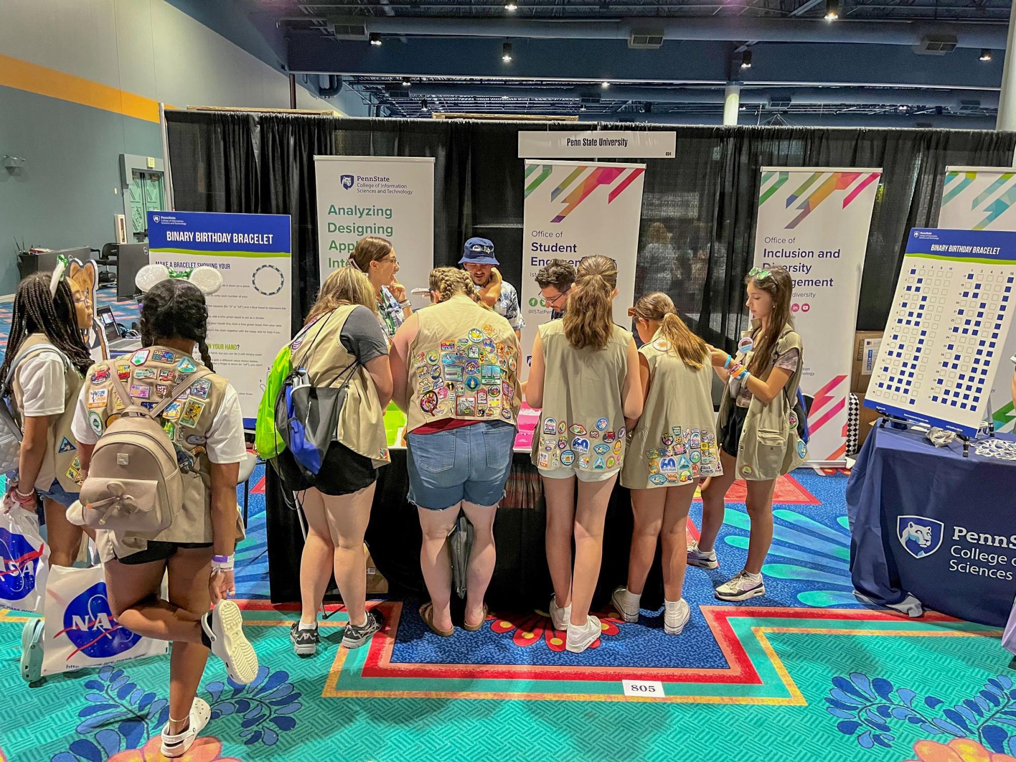 a row of scouts works on an activity at a convention booth