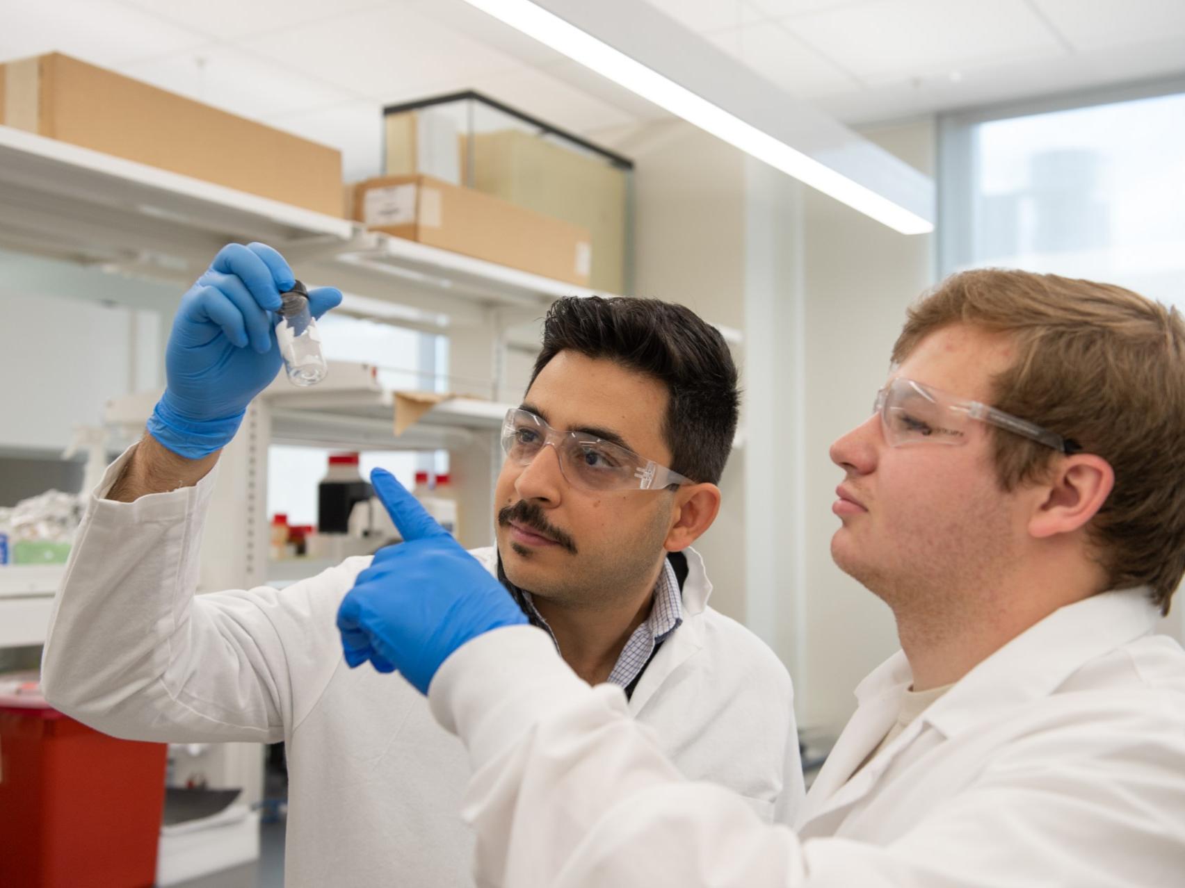 Two men looking at a vial in a lab