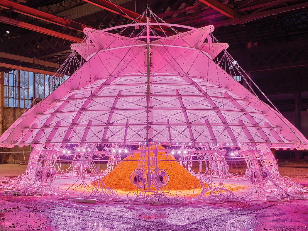 An architectural installation that is illuminated with pink and orange lights.