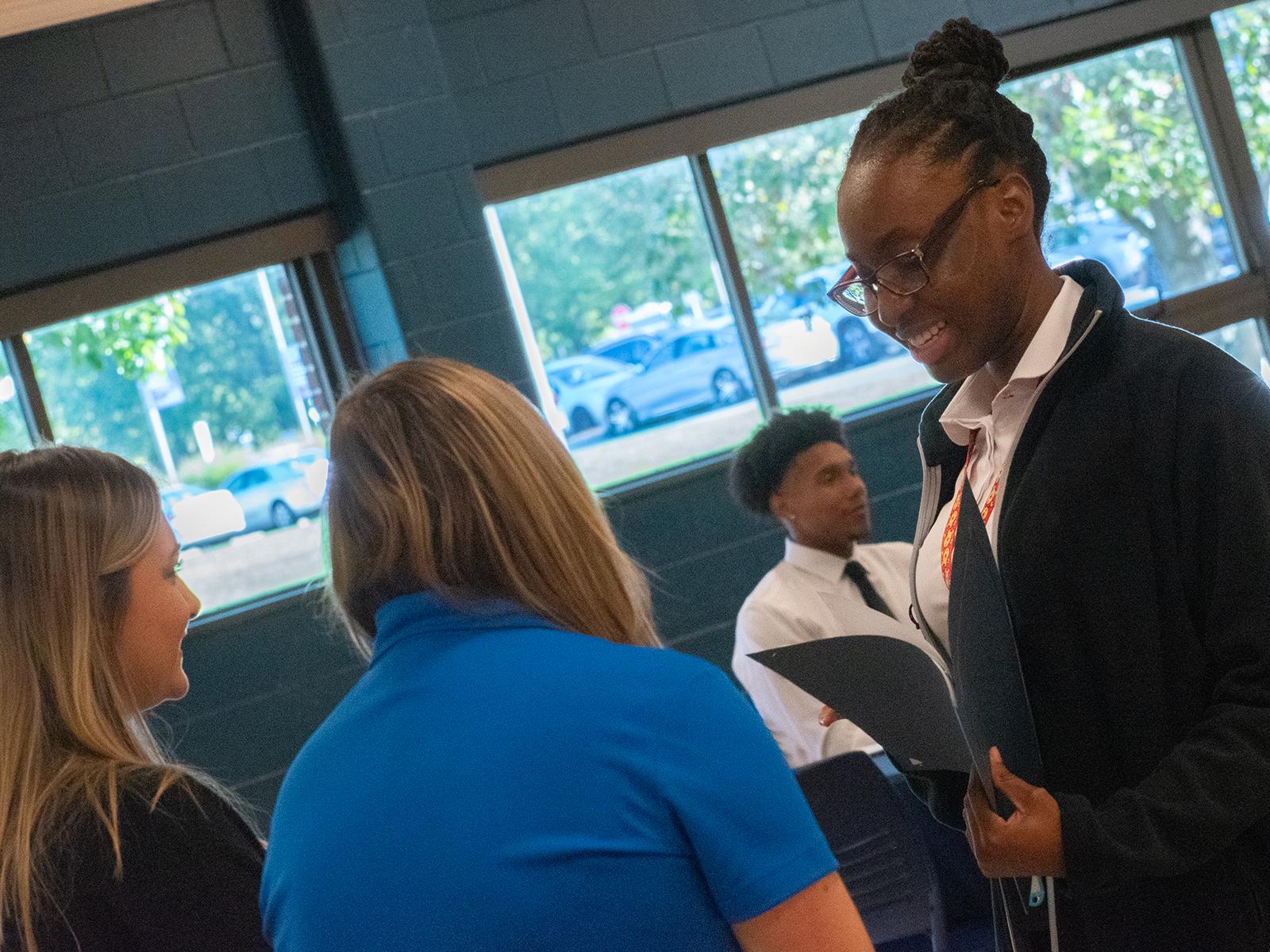 A student talks with company representatives during a career fair