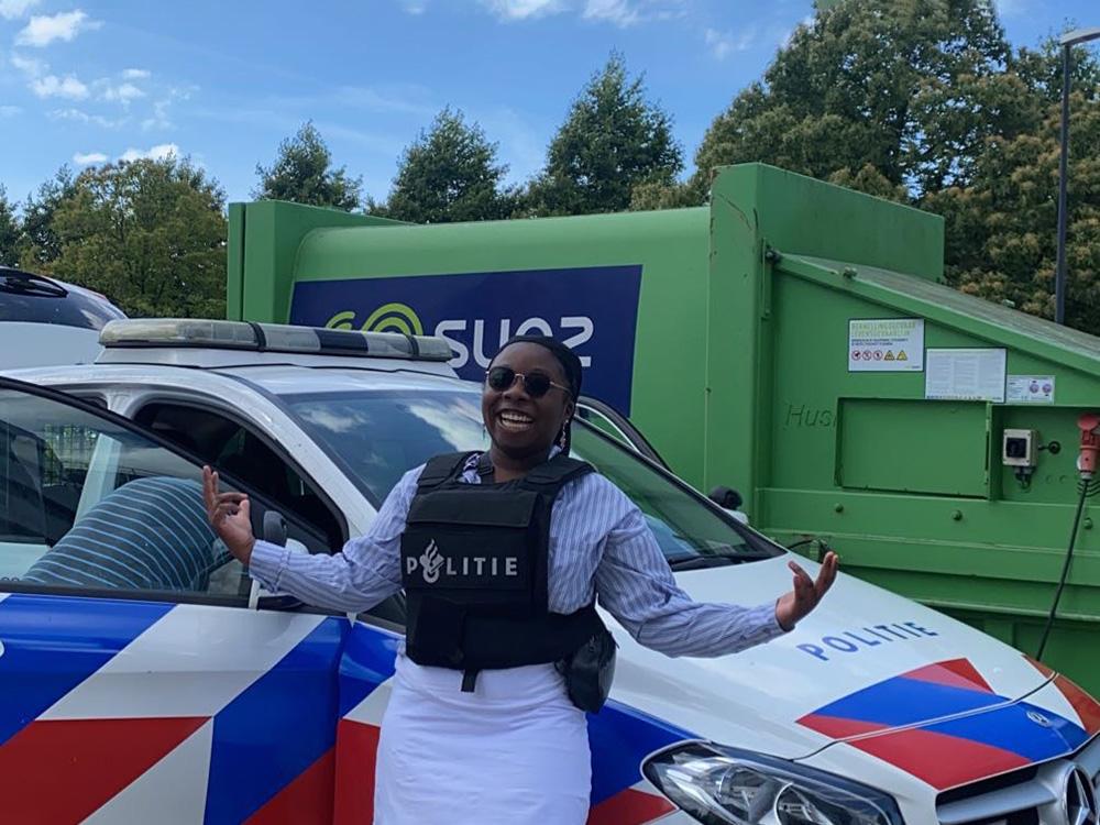 Student Simone Miller stands in front of a Dutch police car as part of an educational activity in the Netherlands.