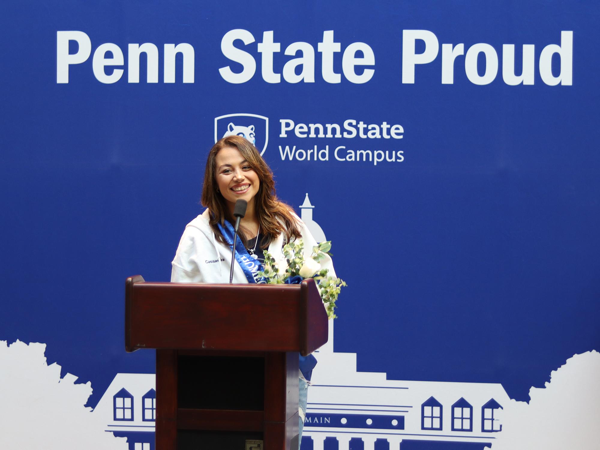 A woman speaks at a podium in front of a blue background.